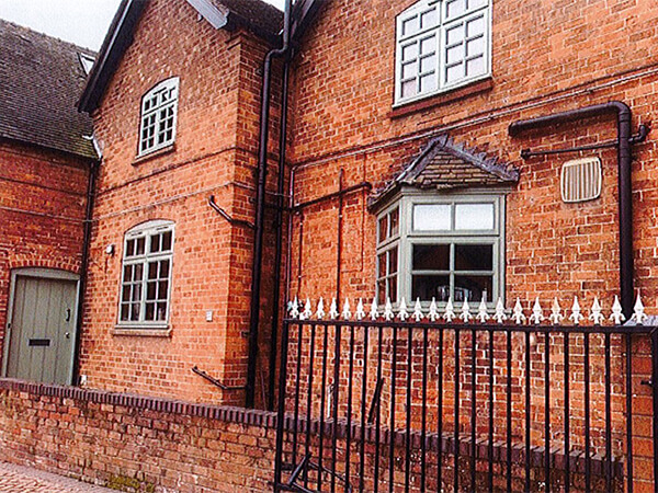 A red brick Worcestershire cottage with its original old green flaking wooden windows and oriel bay.