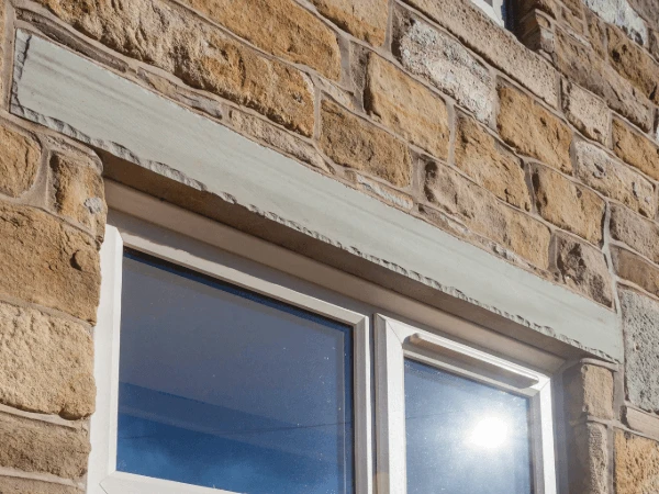 A trickle vent above a window set in a Cotswold stone wall