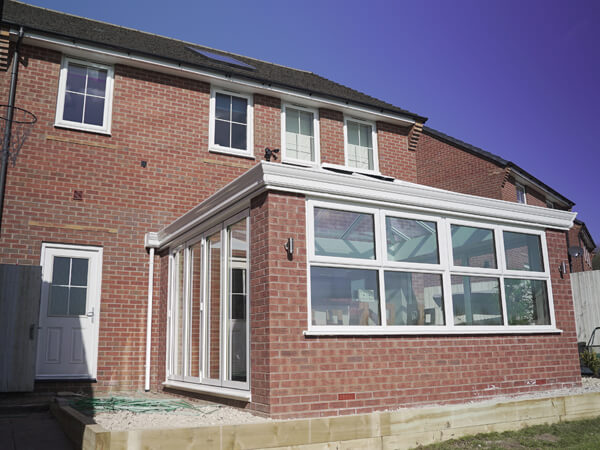 Red Brick House With Matching Extension Conservatory With White Bi Folding Doors And White Windows