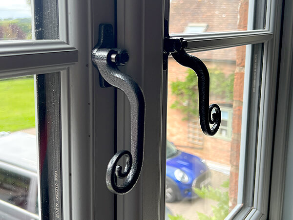 Two lockable Pewter Monkey tail handles, on a High Security, Extreme, Hazy Grey, UPVC double glazed Window with Swiss warm edge spacer bar.
