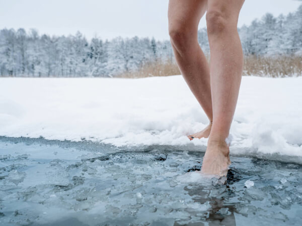 A winter scene with naked legs entering an icy pool