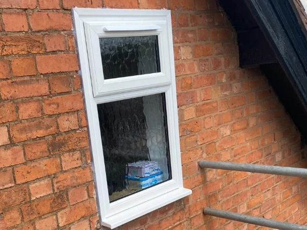 Small white UPVC window with top opener and trickle vent in opening sash