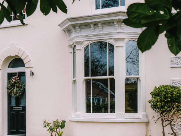 An Ultimate Rose Bay window with arched tops in white set into render with vertical astragal bar