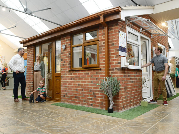 Kidderminster Showroom. The central tiled roof brick extension display, with oak windows and front composite door. To the left a white back door and adjoining window.