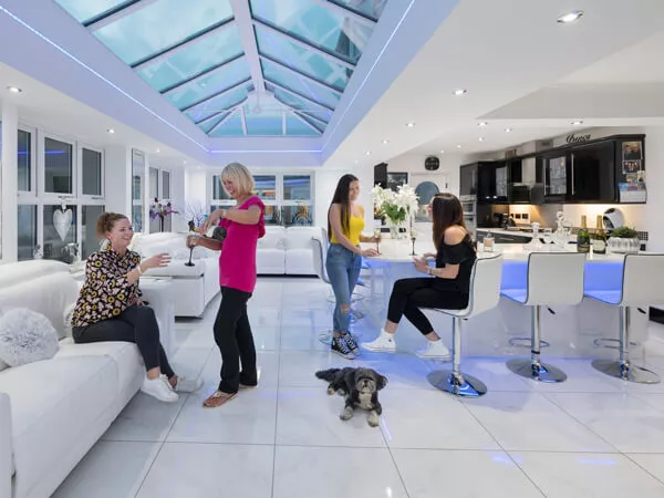 Living Spaces defined here as a kitchen which is open plan to an Orangery in bright white, cream and grey.